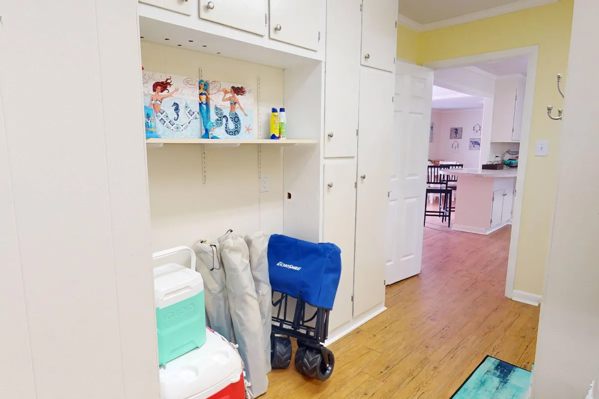 An interior shot featuring organized shelves with colorful artwork, a cooler, and a collapsible cart—essentials for a day at the beach. The space looks practical and inviting, ready for spontaneous outings.